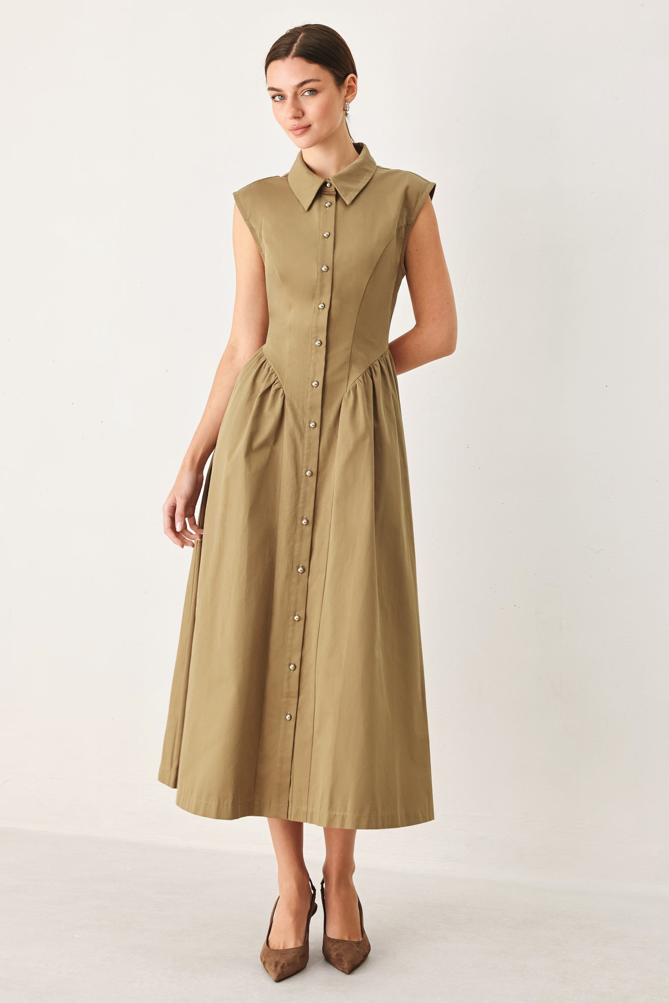 Woman wearing a beige sleeveless dress with buttons on a white background