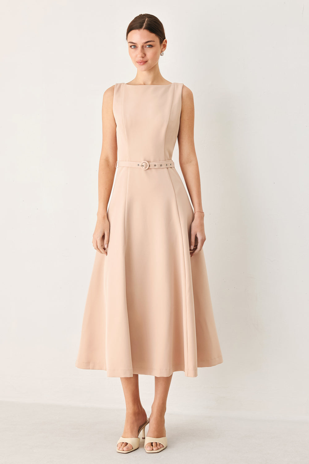 Woman wearing a sleeveless soft blush midi dress  featuring boat neckline, circle skirt, self belt and back zipper closure | FREEMARKET