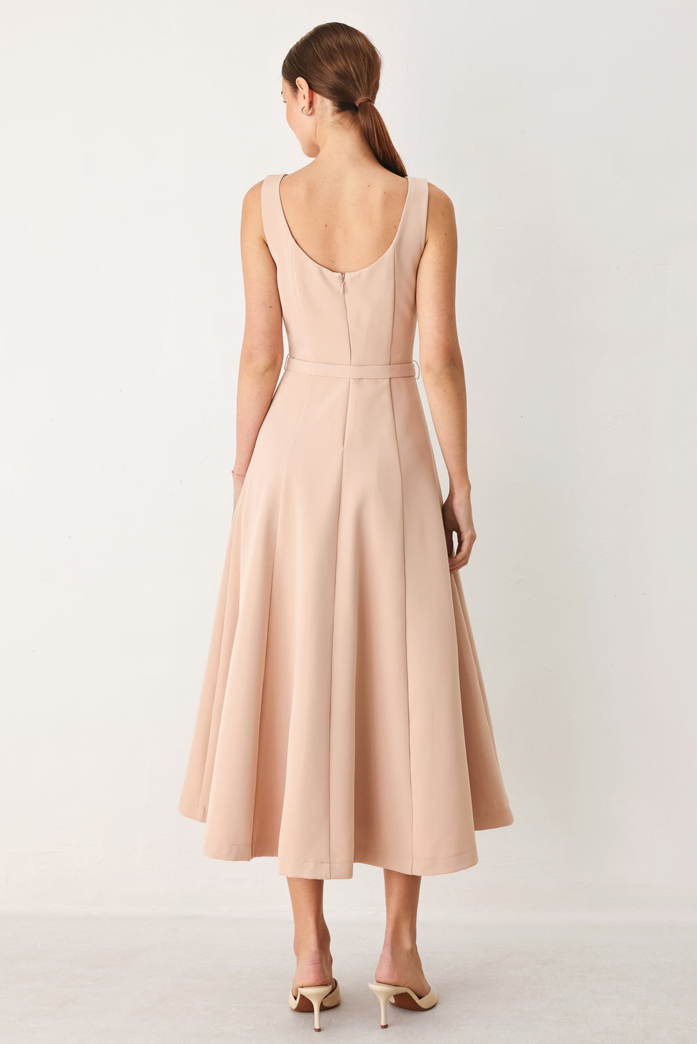 Woman wearing a sleeveless soft blush midi dress  featuring boat neckline, circle skirt, self belt and back zipper closure | FREEMARKET