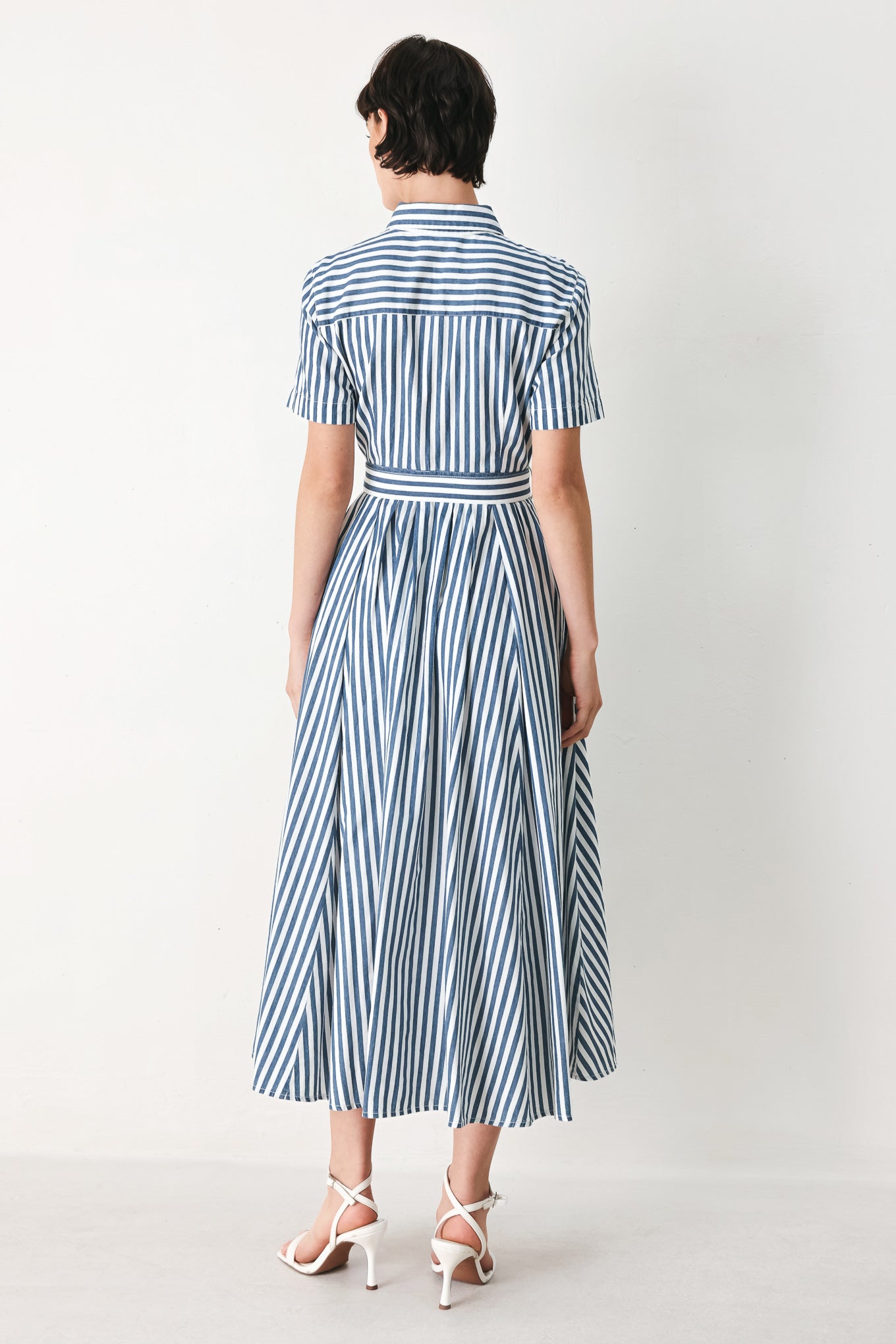 Woman wearing a denim blue and white striped midi shirt dress with self belt and full skirt | FREEMARKET