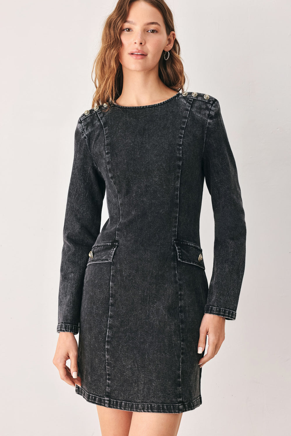 A woman wearing a dark black washed denim mini dress with shoulder embellishments and front patch pockets | FREEMARKET
