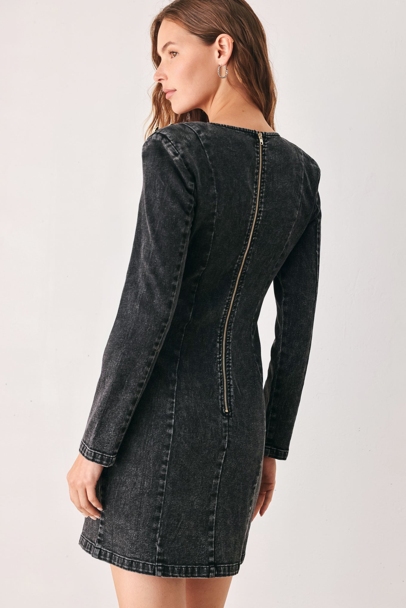 A woman wearing a dark black washed denim mini dress with shoulder embellishments and front patch pockets | FREEMARKET