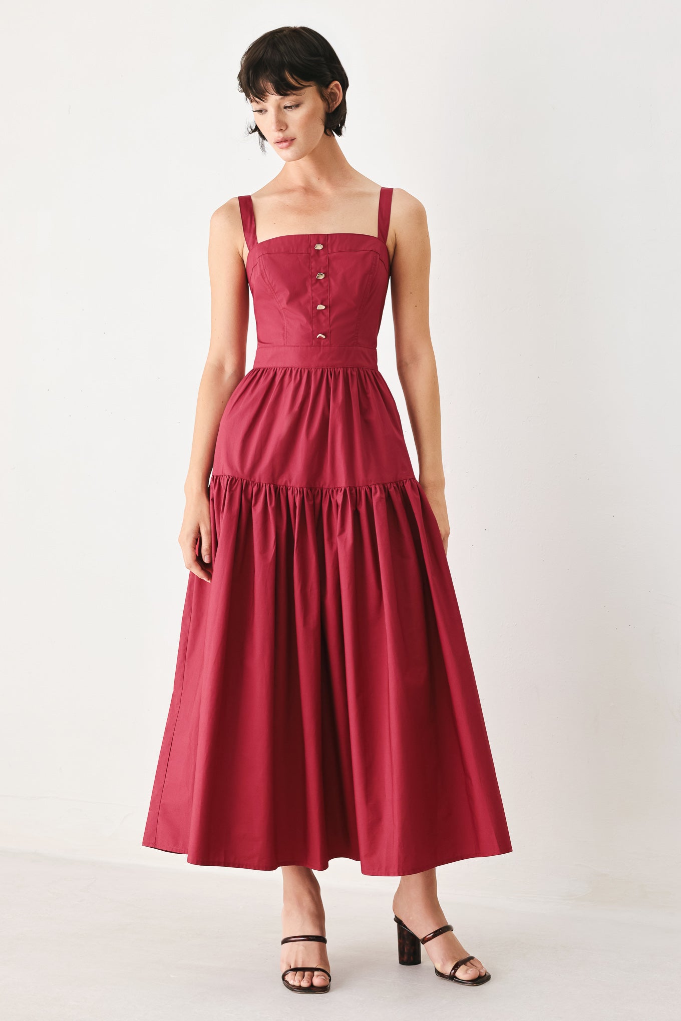 Woman wearing a burgundy red midi dress featuring straight neckline, straps, front button detail, single tier and back zipper | FREEMARKET
