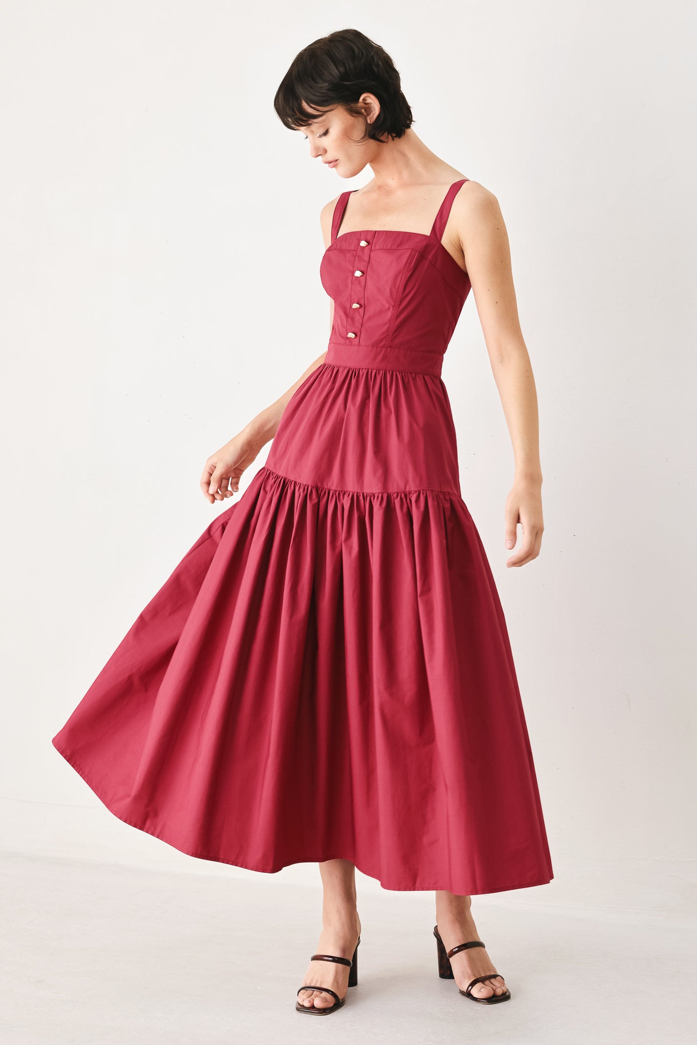 Woman wearing a burgundy red midi dress featuring straight neckline, straps, front button detail, single tier and back zipper | FREEMARKET