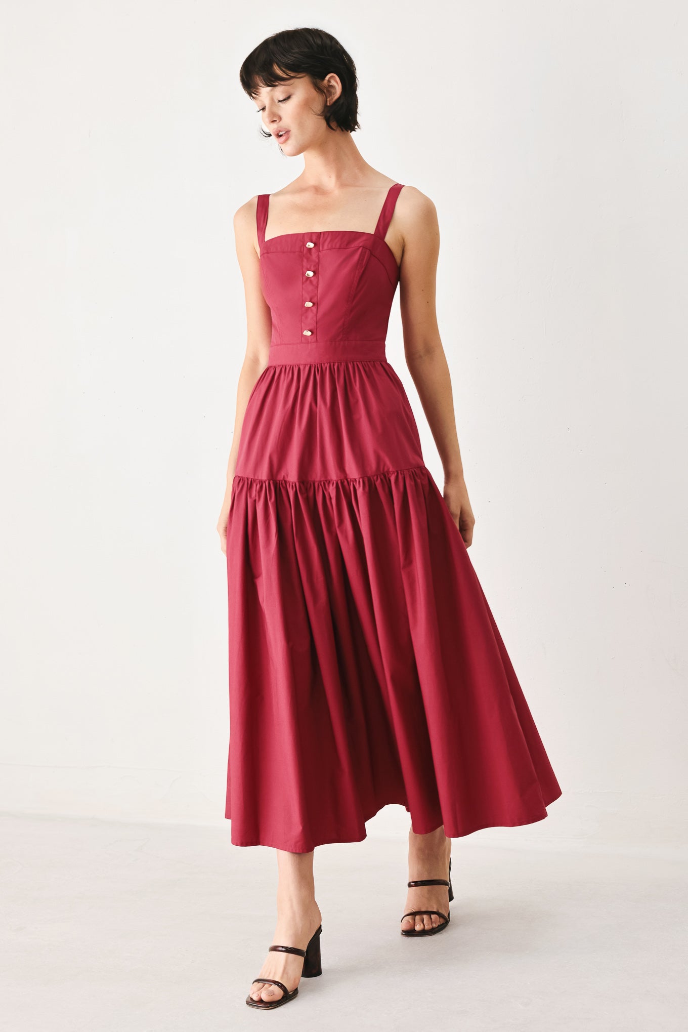 Woman wearing a burgundy red midi dress featuring straight neckline, straps, front button detail, single tier and back zipper | FREEMARKET
