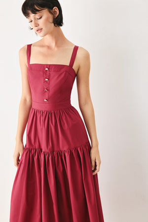 Woman wearing a burgundy red midi dress featuring straight neckline, straps, front button detail, single tier and back zipper | FREEMARKET