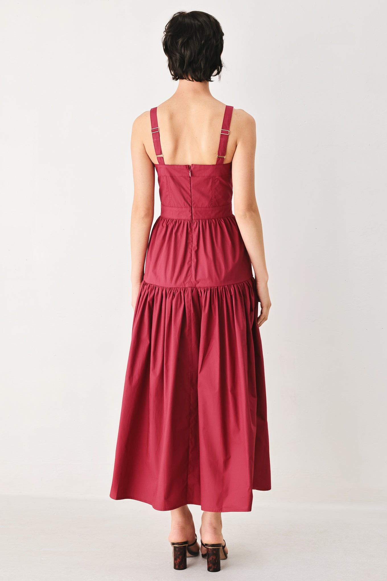 Woman wearing a burgundy red midi dress featuring straight neckline, straps, front button detail, single tier and back zipper | FREEMARKET