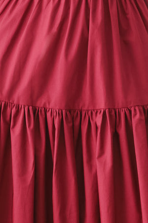 Woman wearing a burgundy red midi dress featuring straight neckline, straps, front button detail, single tier and back zipper | FREEMARKET