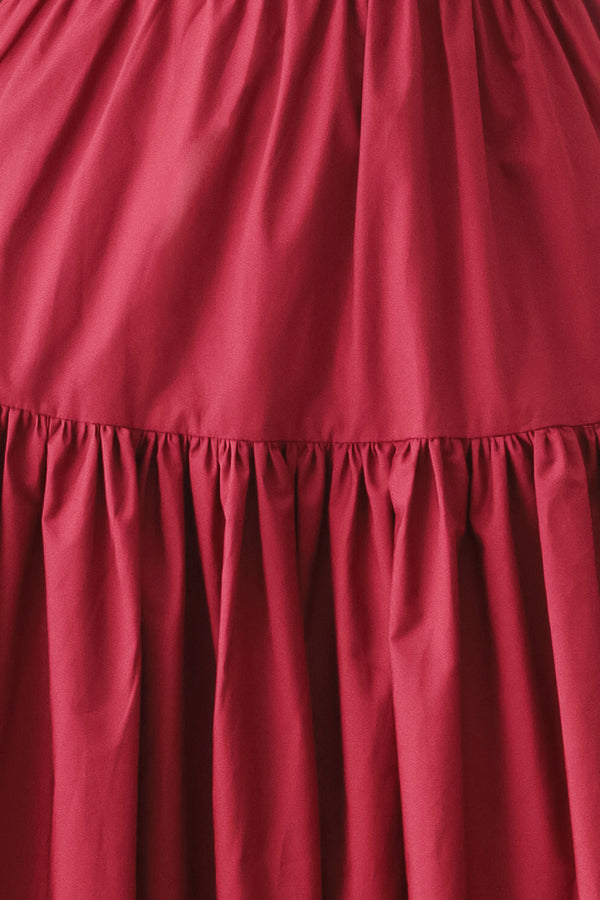 Woman wearing a burgundy red midi dress featuring straight neckline, straps, front button detail, single tier and back zipper | FREEMARKET