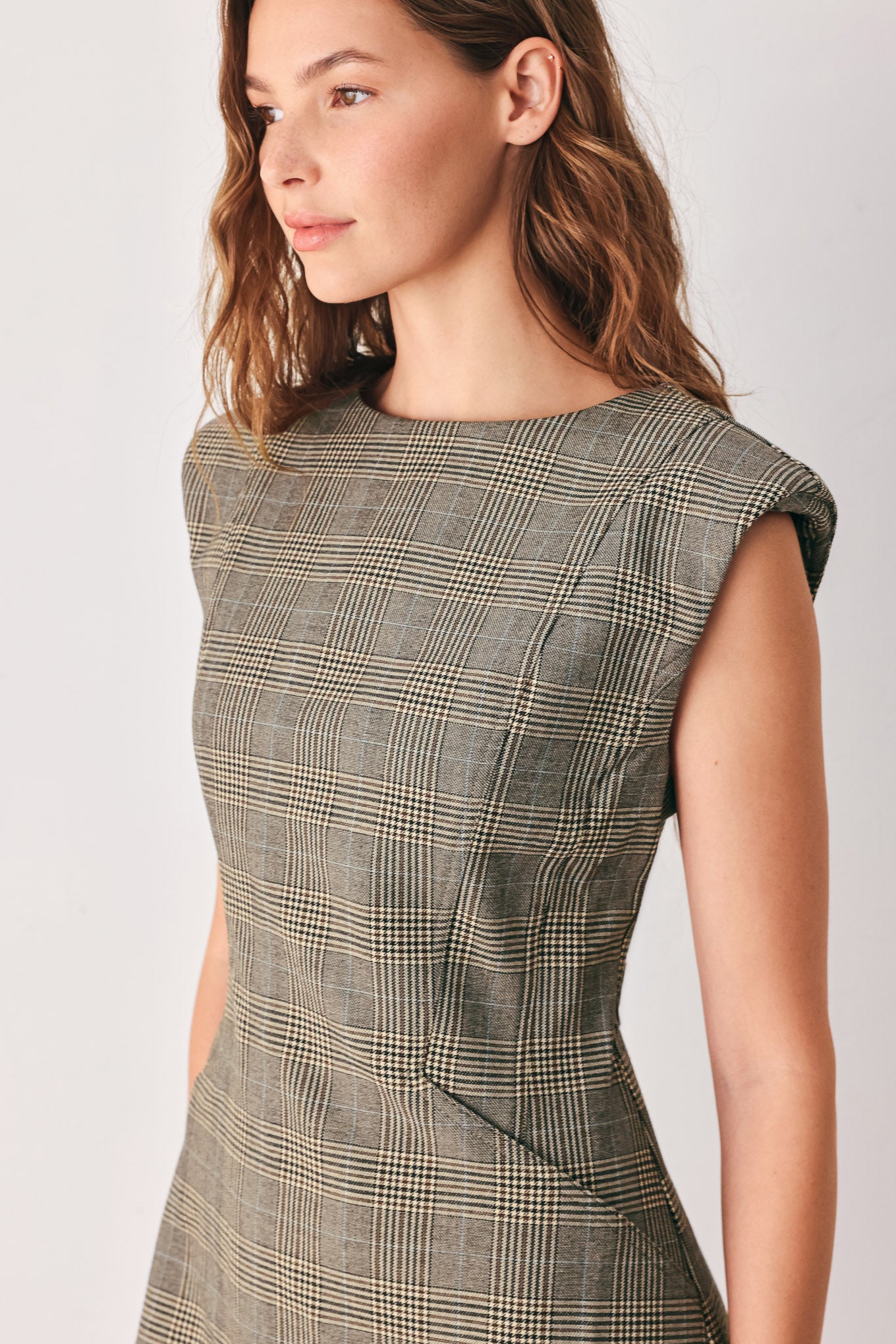 A woman wearing a sleeveless, min gray plaid dress with structured shoulders | FREEMARKET