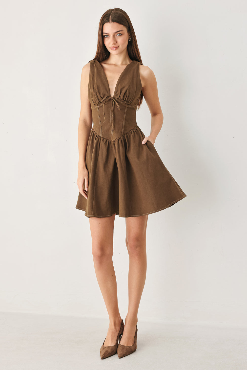 Woman wearing a washed brown woven mini dress featuring V neckline with tie, sleeveless, corset waist, full skirt and back zipper closure | FREEMARKET