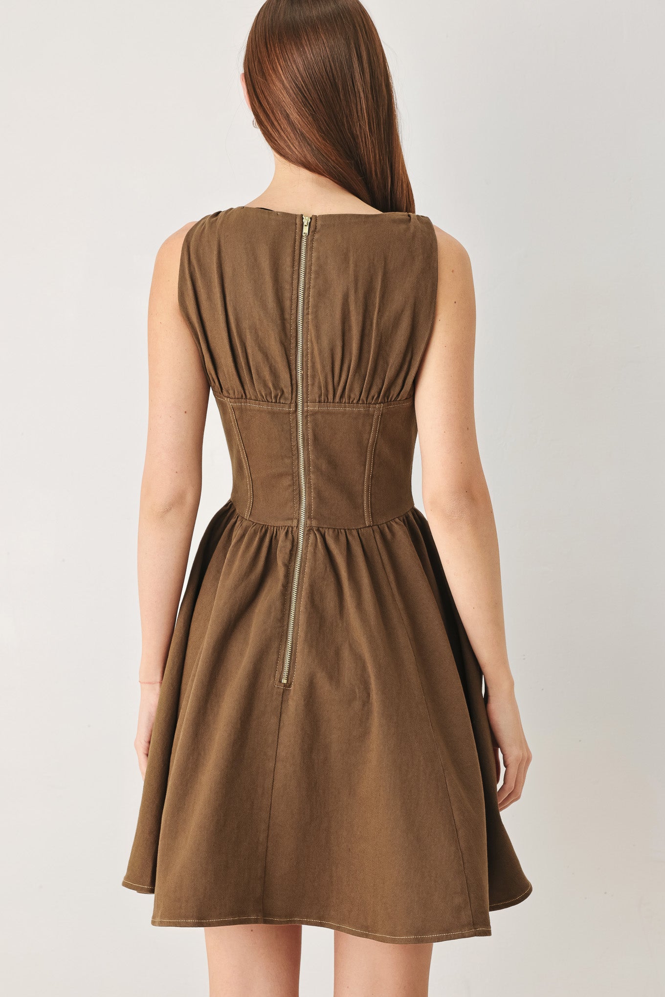 Woman wearing a washed brown woven mini dress featuring V neckline with tie, sleeveless, corset waist, full skirt and back zipper closure | FREEMARKET