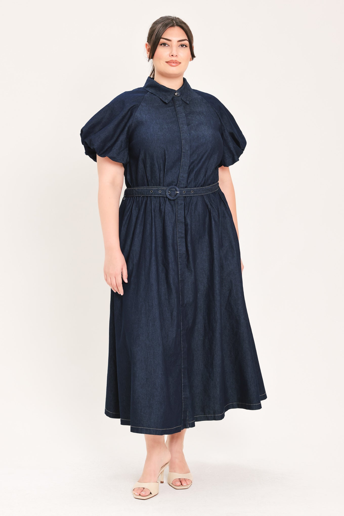 A woman models a dark indigo denim midi shirt dress with short puff sleeves, a pointed collar, and a matching dark belt | FREEMARKET Curve