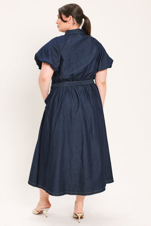 A woman models a dark indigo denim midi shirt dress with short puff sleeves, a pointed collar, and a matching dark belt | FREEMARKET Curve