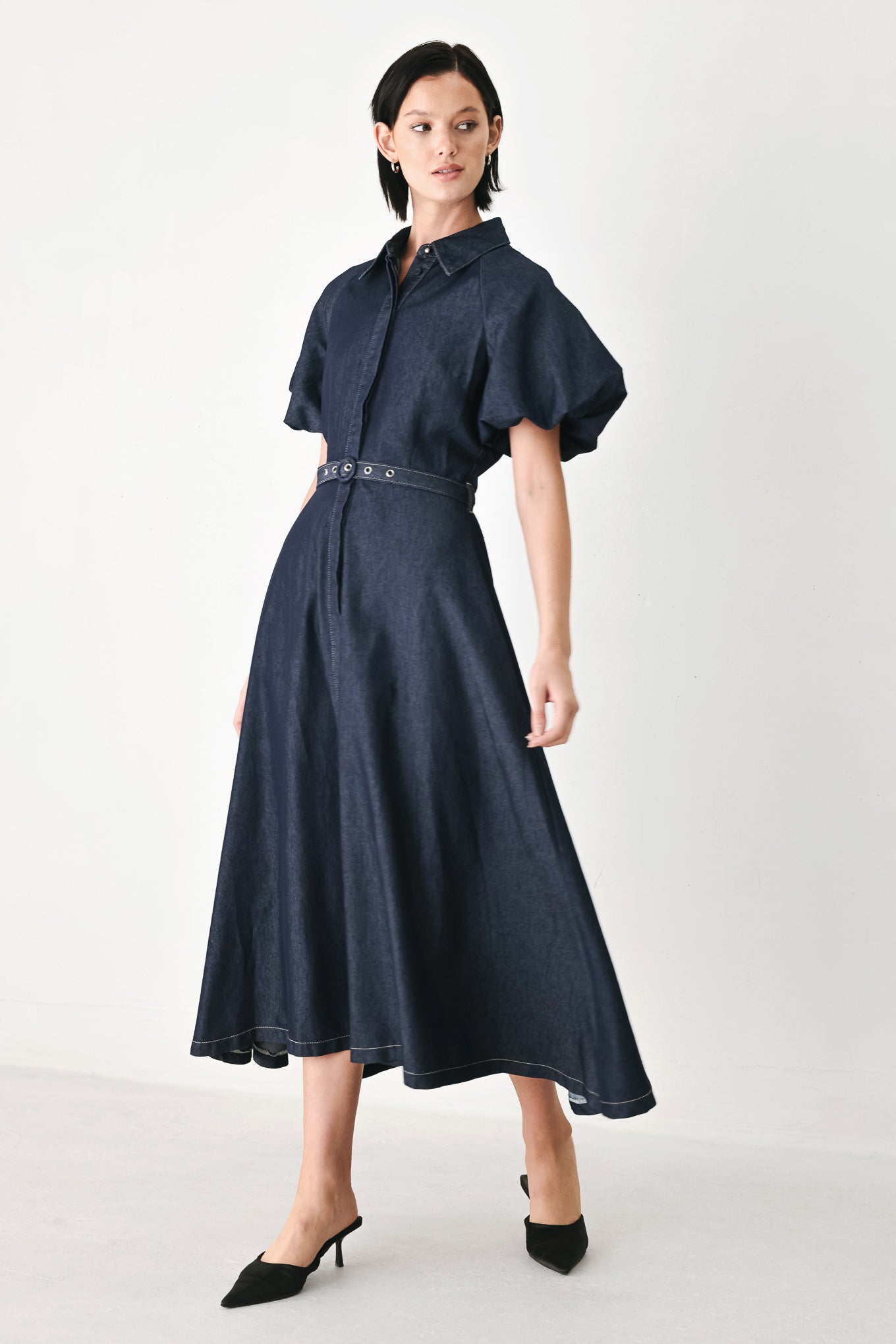 A woman models a dark indigo denim midi shirt dress with short puff sleeves, a pointed collar, and a matching dark belt | FREEMARKET