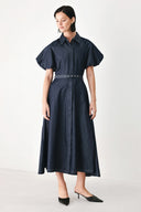 A woman models a dark indigo denim midi shirt dress with short puff sleeves, a pointed collar, and a matching dark belt | FREEMARKET