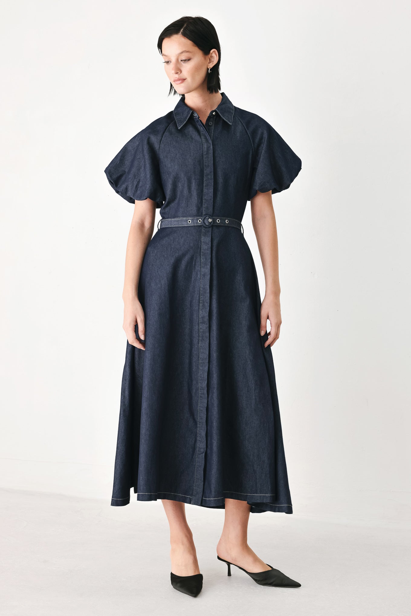 A woman models a dark indigo denim midi shirt dress with short puff sleeves, a pointed collar, and a matching dark belt | FREEMARKET