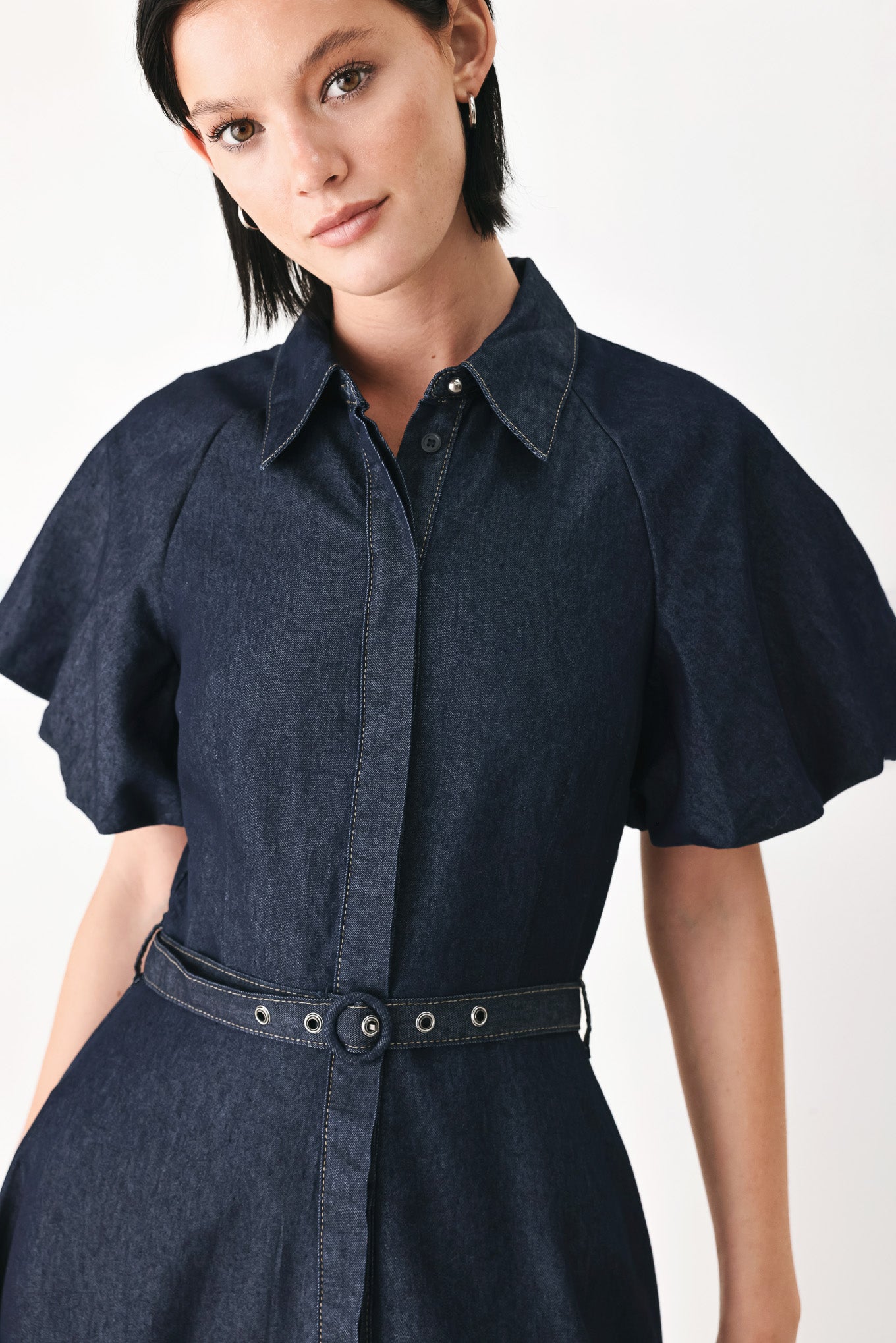 A woman models a dark indigo denim midi shirt dress with short puff sleeves, a pointed collar, and a matching dark belt | FREEMARKET