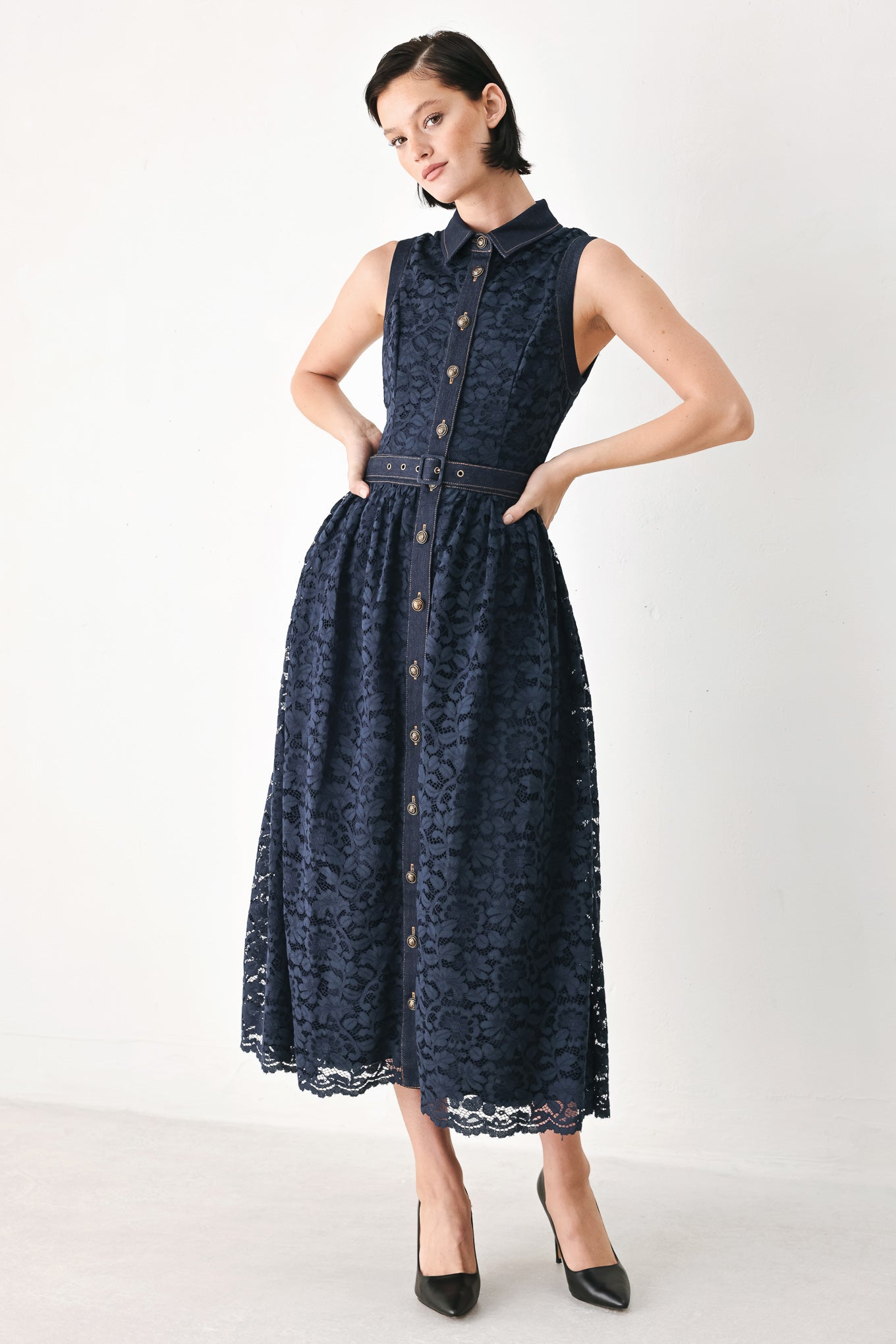 A woman modeling a sleeveless navy midi dress with a lace overlay, button-front bodice, and matching belt | FREEMARKET