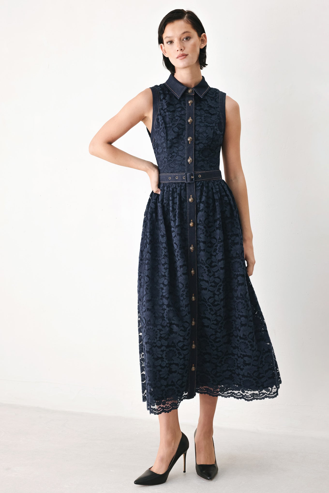 A woman modeling a sleeveless navy midi dress with a lace overlay, button-front bodice, and matching belt | FREEMARKET