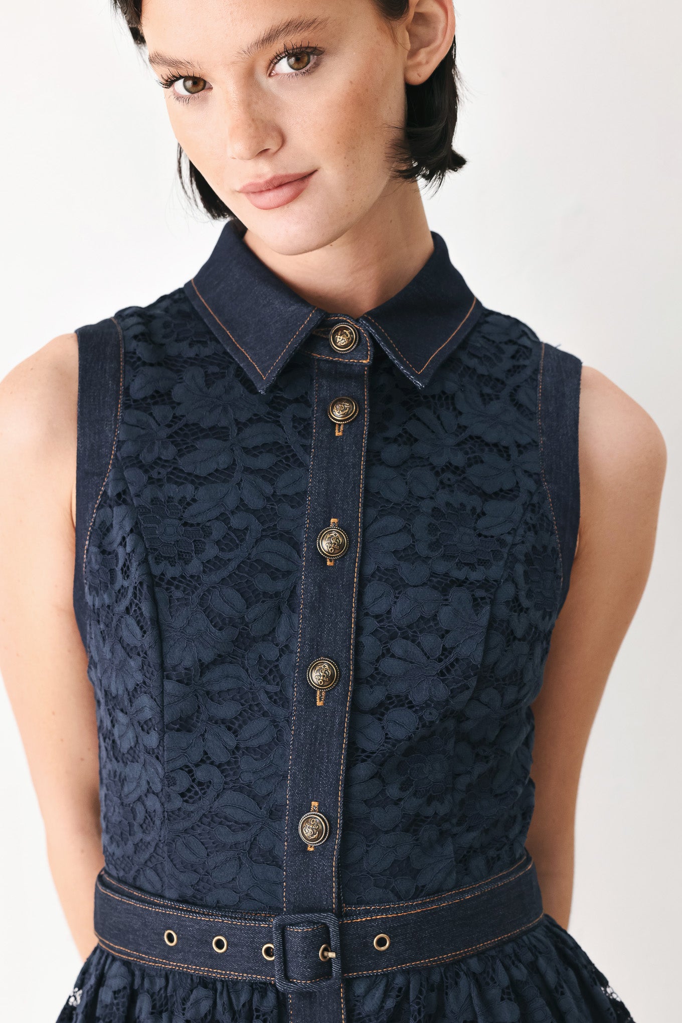 A woman modeling a sleeveless navy midi dress with a lace overlay, button-front bodice, and matching belt | FREEMARKET