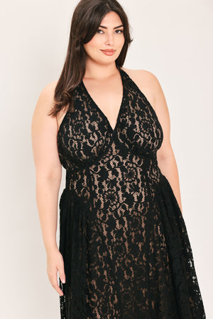 A woman modeling a sleeveless black lace halter maxi dress with a deep V-neckline, holding a small black handbag against a plain light background | FREEMARKET Curve