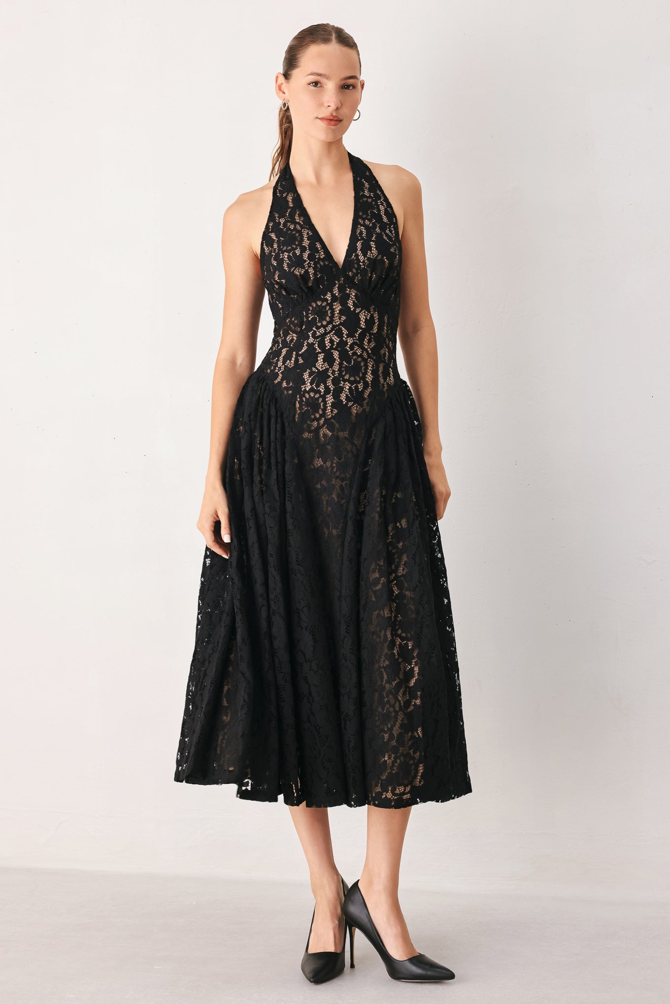 A woman wearing a sleeveless black lace halter midi dress with a deep V-neckline and flared skirt | FREEMARKET