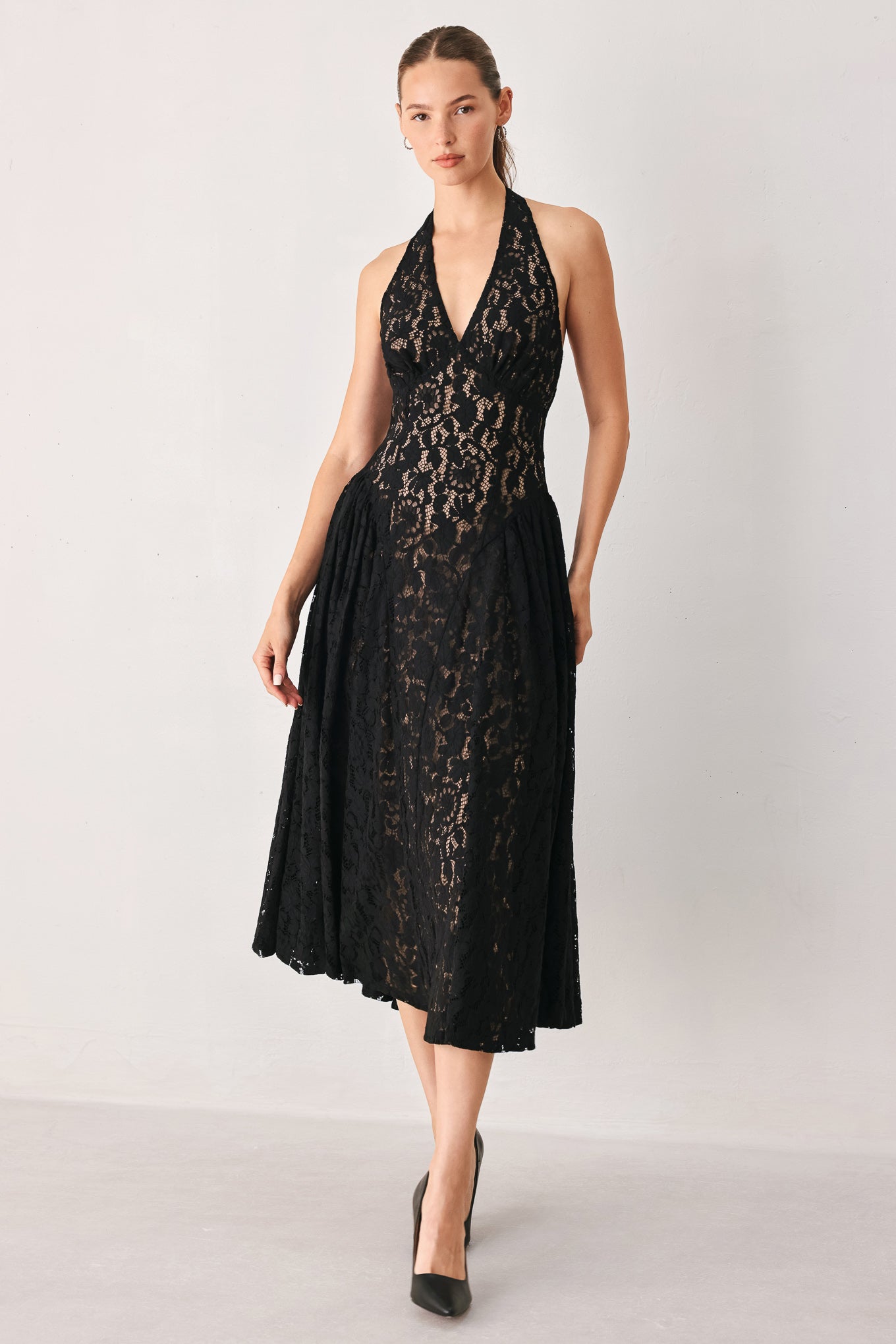 A woman wearing a sleeveless black lace halter midi dress with a deep V-neckline and flared skirt | FREEMARKET
