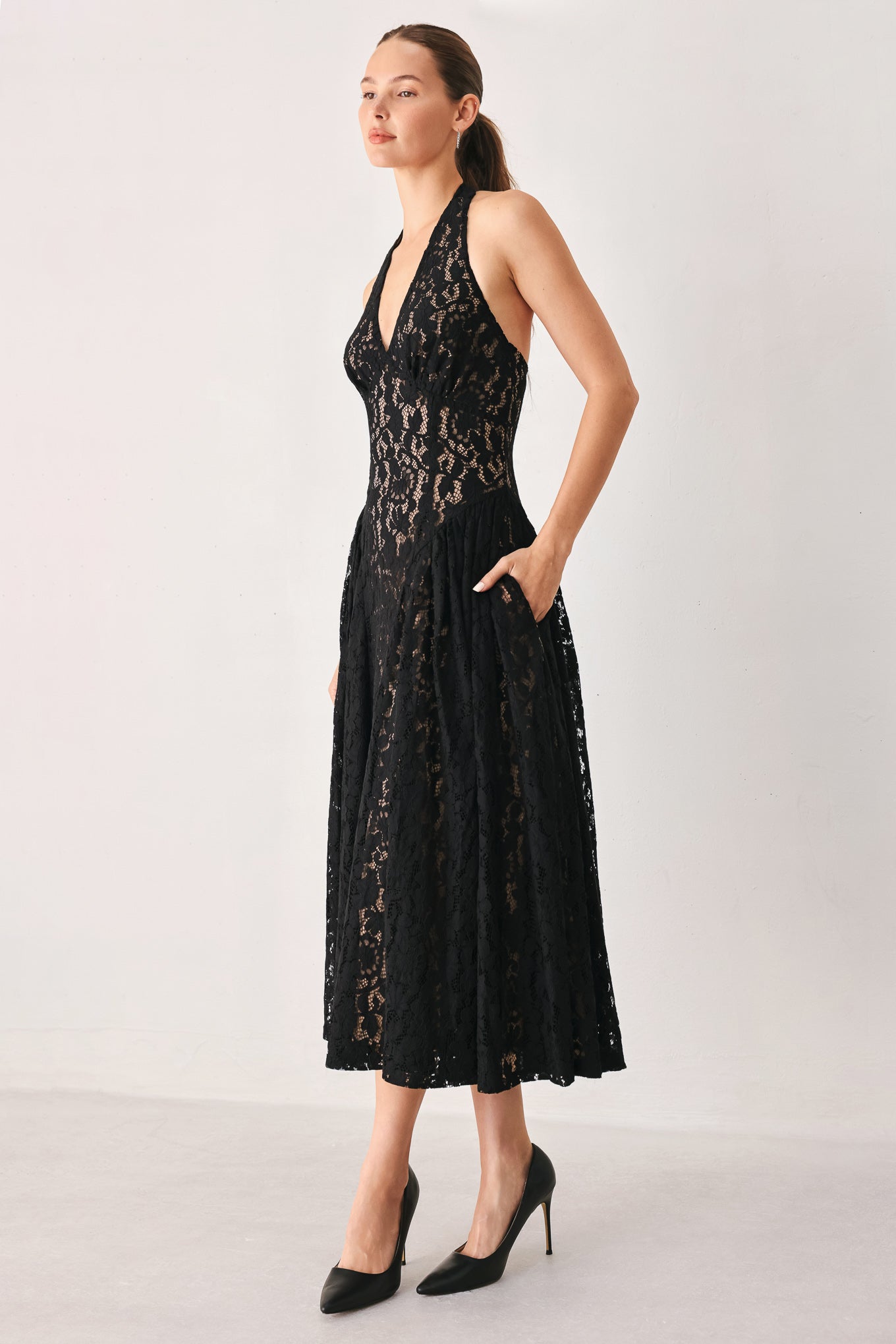 A woman wearing a sleeveless black lace halter midi dress with a deep V-neckline and flared skirt | FREEMARKET