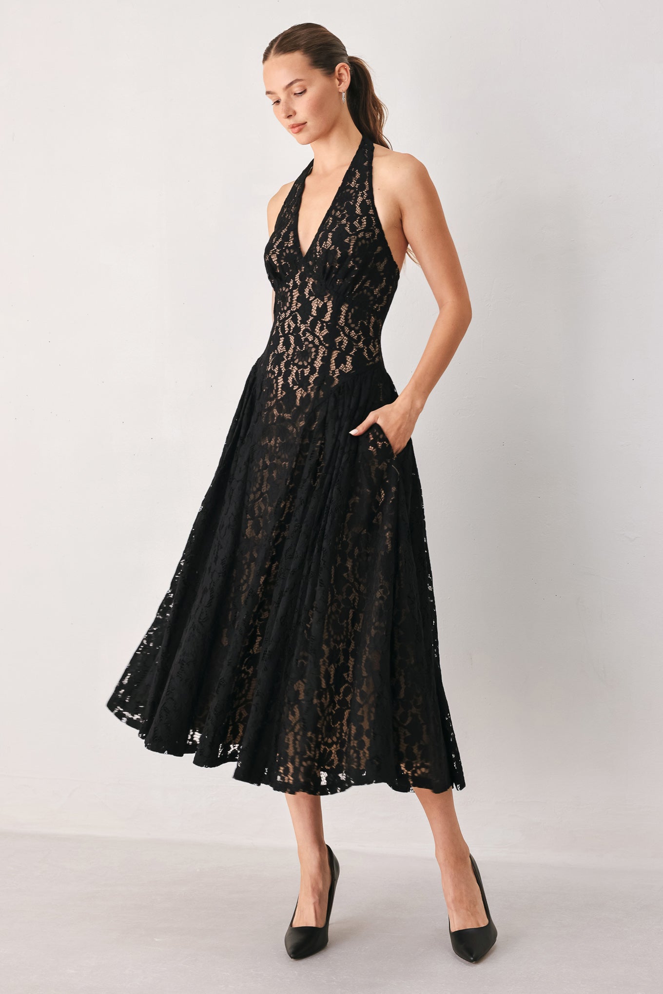 A woman wearing a sleeveless black lace halter midi dress with a deep V-neckline and flared skirt | FREEMARKET