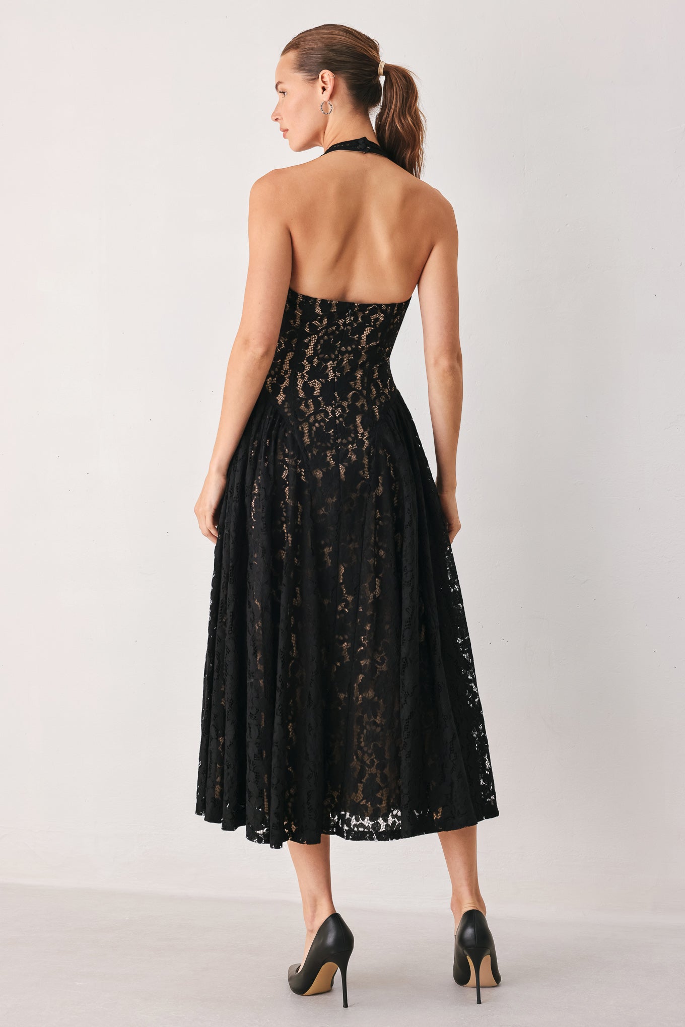A woman wearing a sleeveless black lace halter midi dress with a deep V-neckline and flared skirt | FREEMARKET