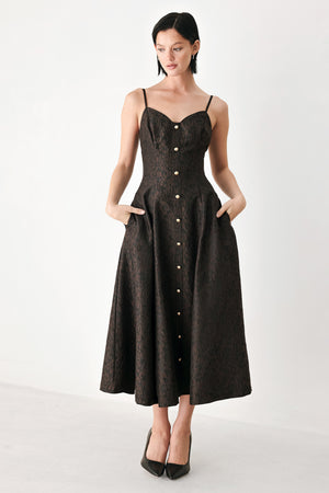 A woman modeling a black midi dress with a textured jacquard leopard pattern, featuring thin spaghetti straps, a sweetheart neckline, a button-down front, and side pockets | FREEMARKET