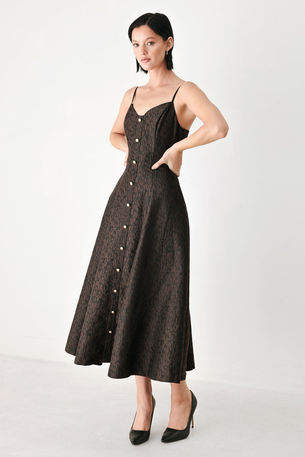 A woman modeling a black midi dress with a textured jacquard leopard pattern, featuring thin spaghetti straps, a sweetheart neckline, a button-down front, and side pockets | FREEMARKET