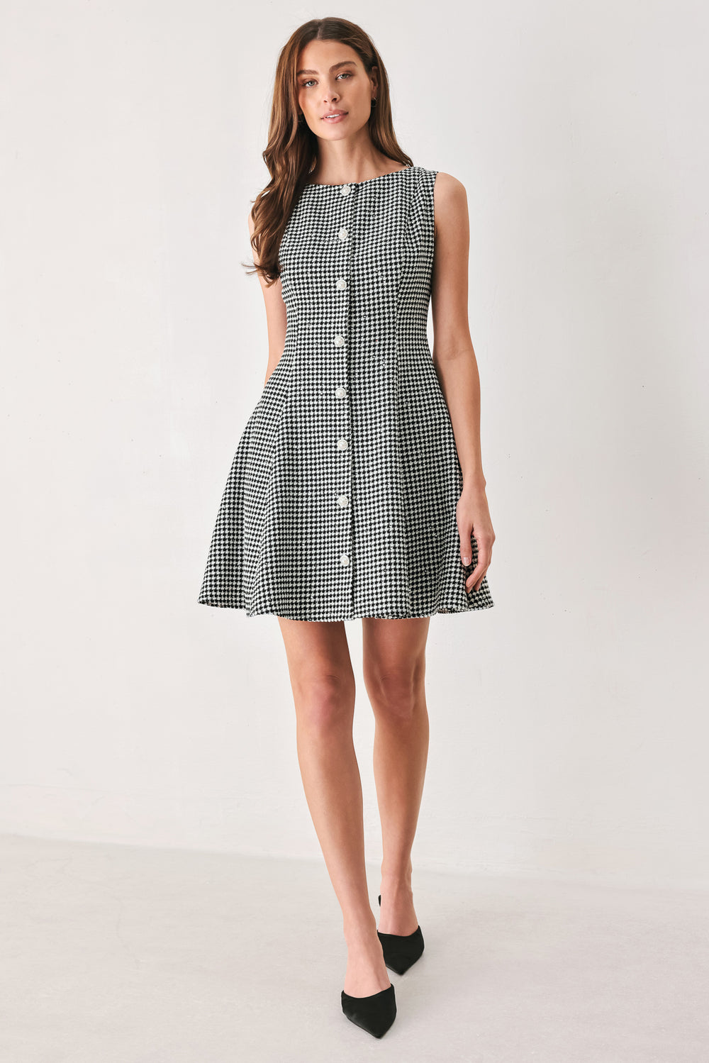 Woman wearing a black and white houndstooth sleeveless mini dress with buttons along the front and sequins | FREEMARKET