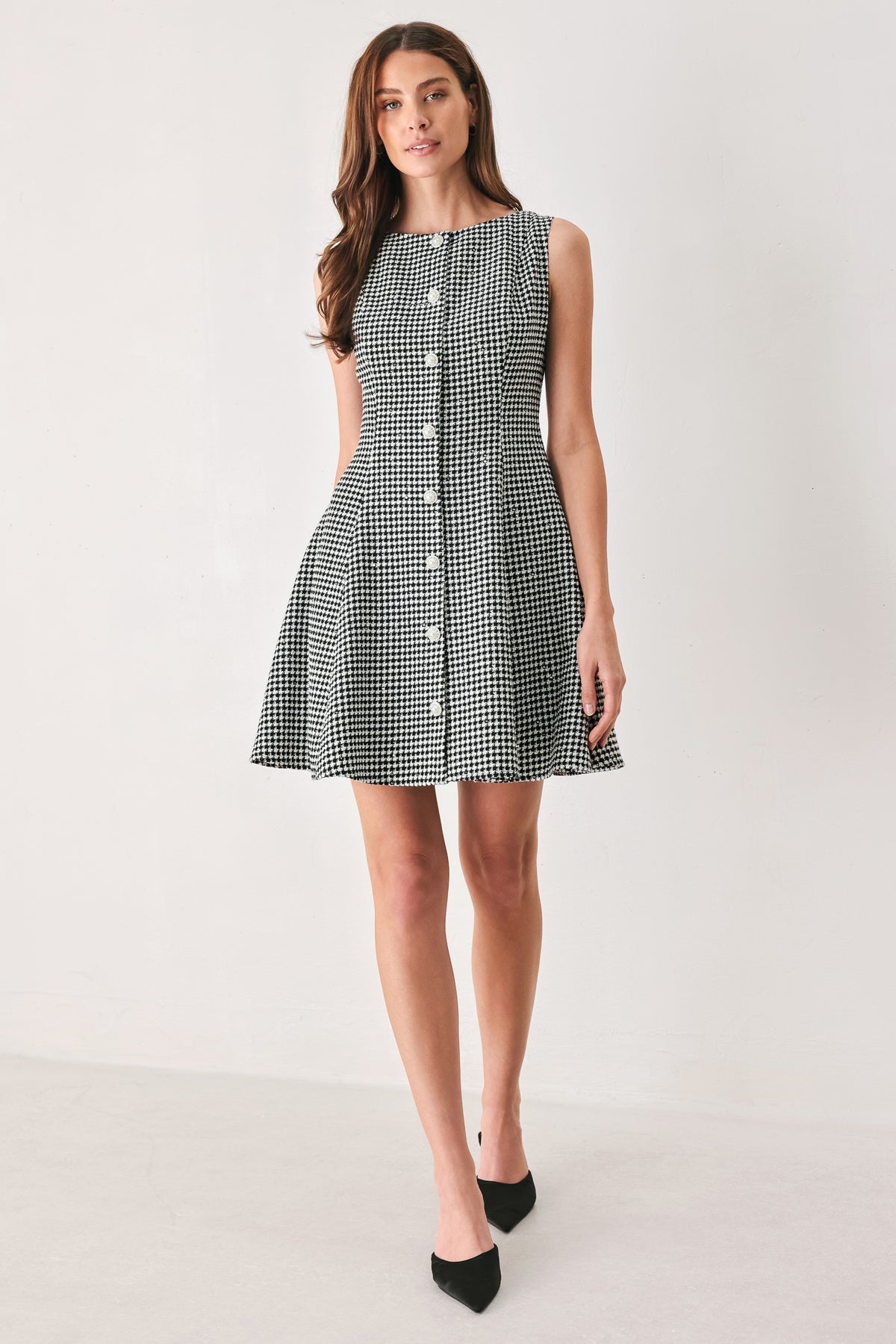 Woman wearing a black and white houndstooth sleeveless mini dress with buttons along the front and sequins | FREEMARKET