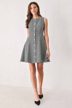 Woman wearing a black and white houndstooth sleeveless mini dress with buttons along the front and sequins | FREEMARKET