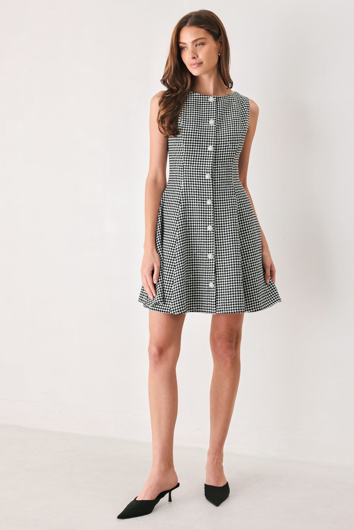 Woman wearing a black and white houndstooth sleeveless mini dress with buttons along the front and sequins | FREEMARKET