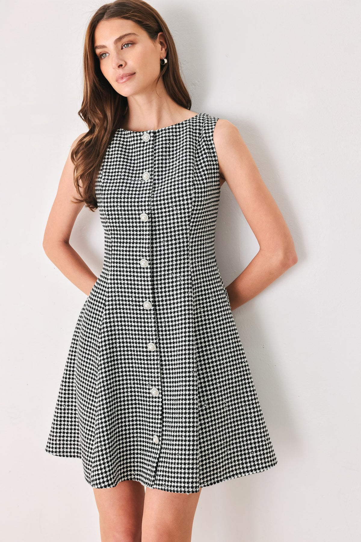 Woman wearing a black and white houndstooth sleeveless mini dress with buttons along the front and sequins | FREEMARKET