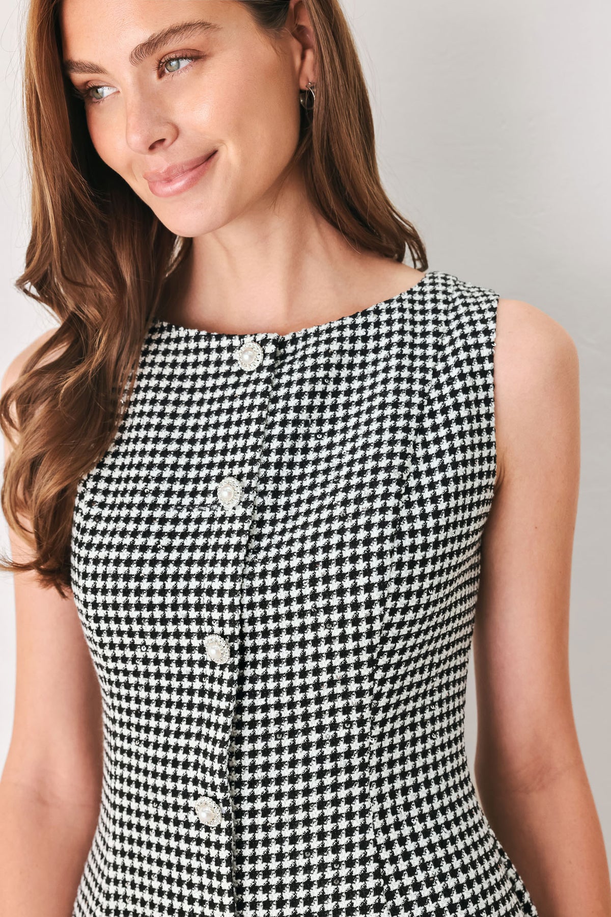 Woman wearing a black and white houndstooth sleeveless mini dress with buttons along the front and sequins | FREEMARKET