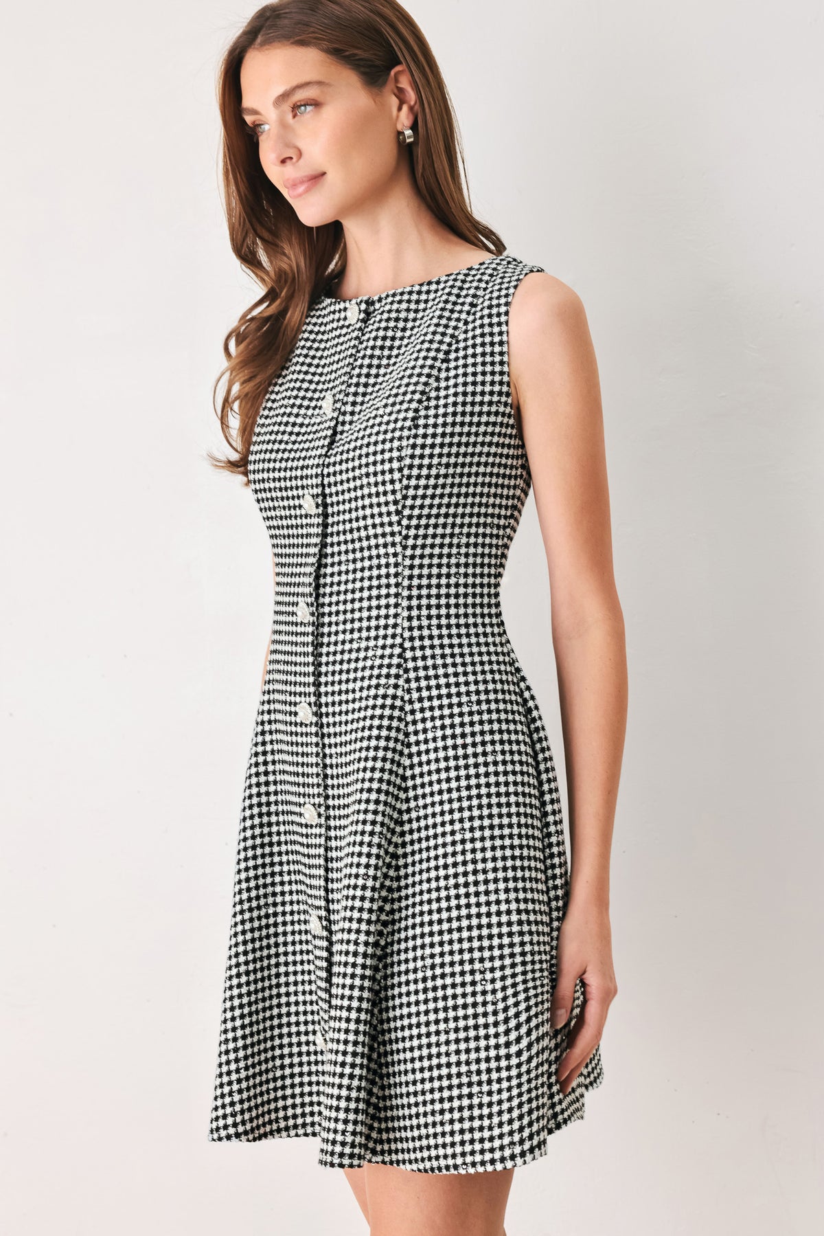 Woman wearing a black and white houndstooth sleeveless mini dress with buttons along the front and sequins | FREEMARKET