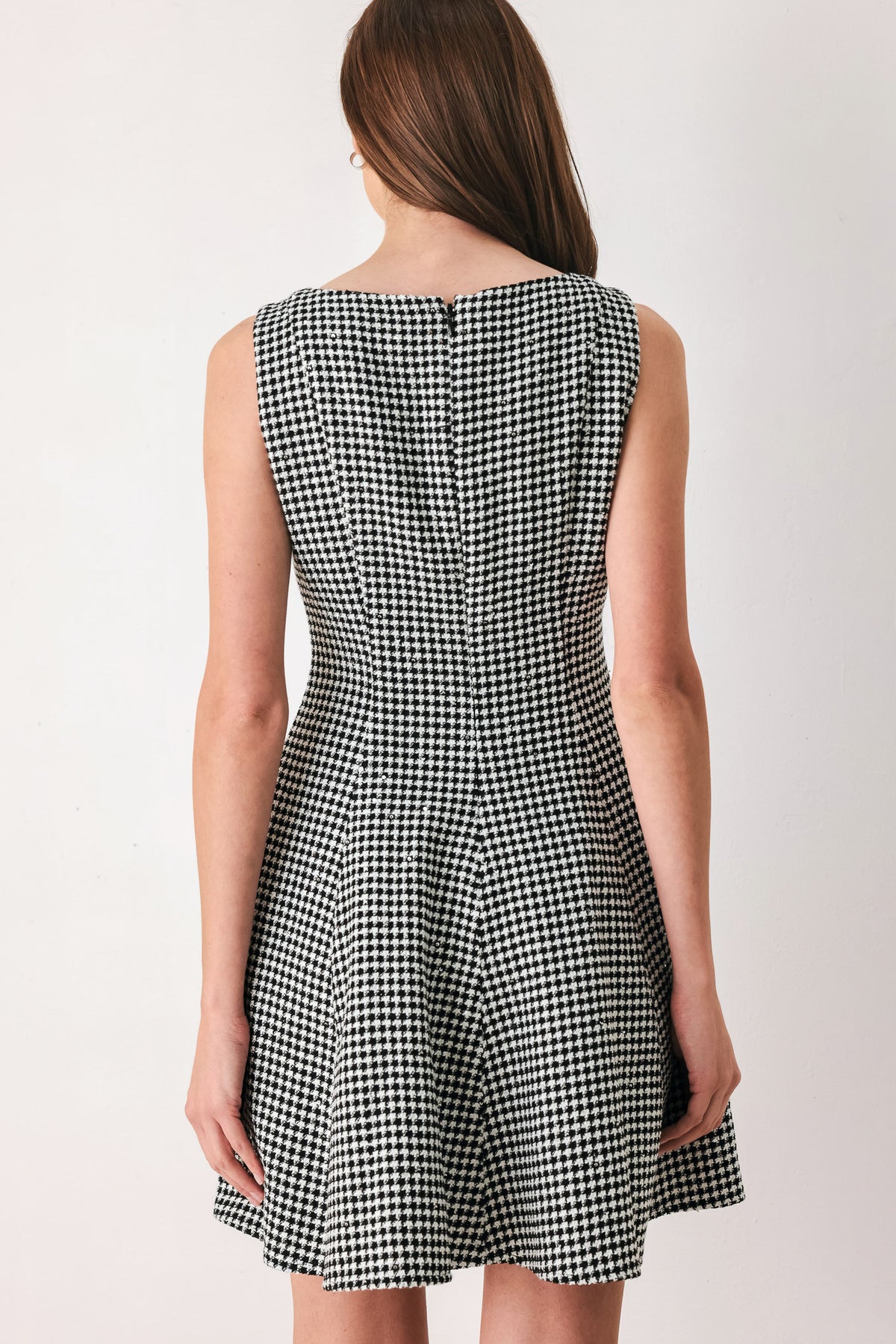 Woman wearing a black and white houndstooth sleeveless mini dress with buttons along the front and sequins | FREEMARKET