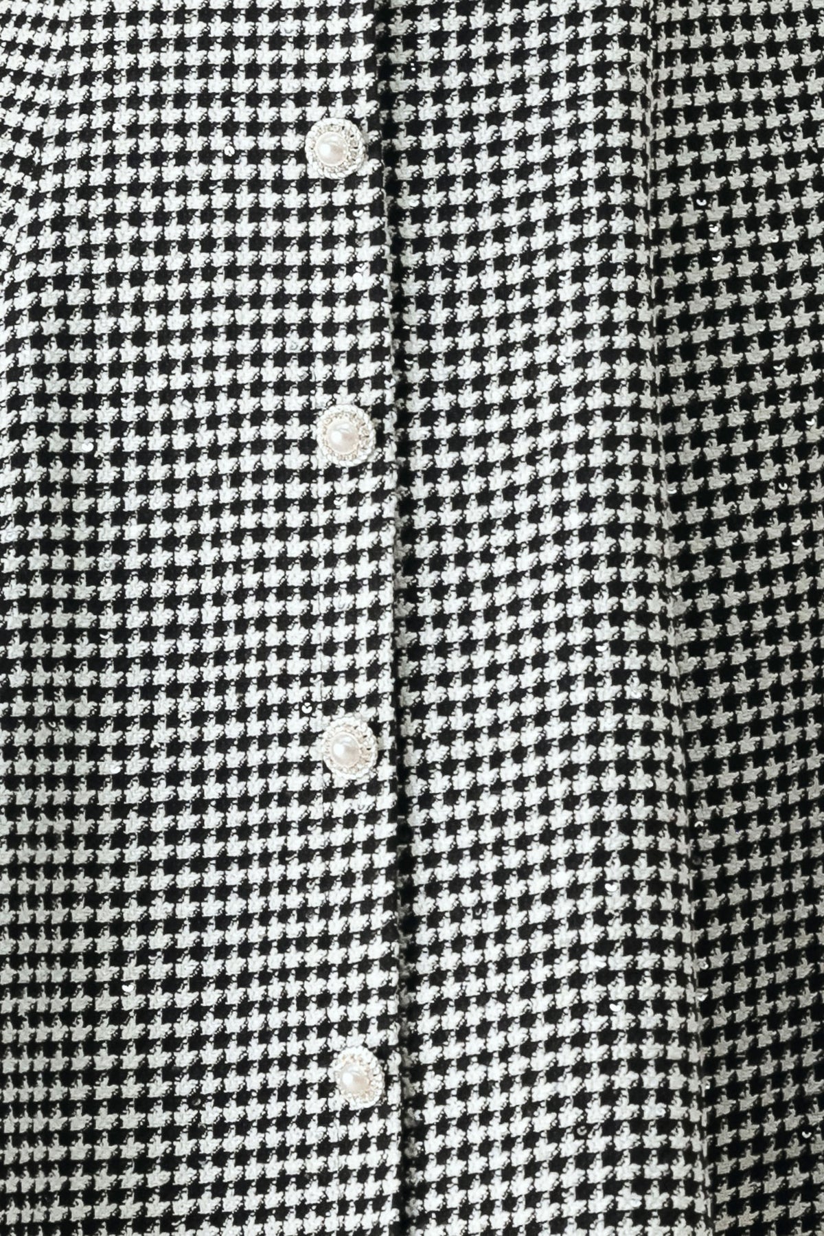 Woman wearing a black and white houndstooth sleeveless mini dress with buttons along the front and sequins | FREEMARKET