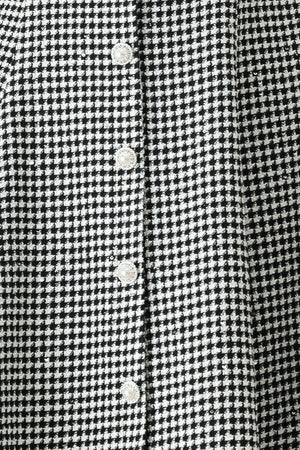 Woman wearing a black and white houndstooth sleeveless mini dress with buttons along the front and sequins | FREEMARKET