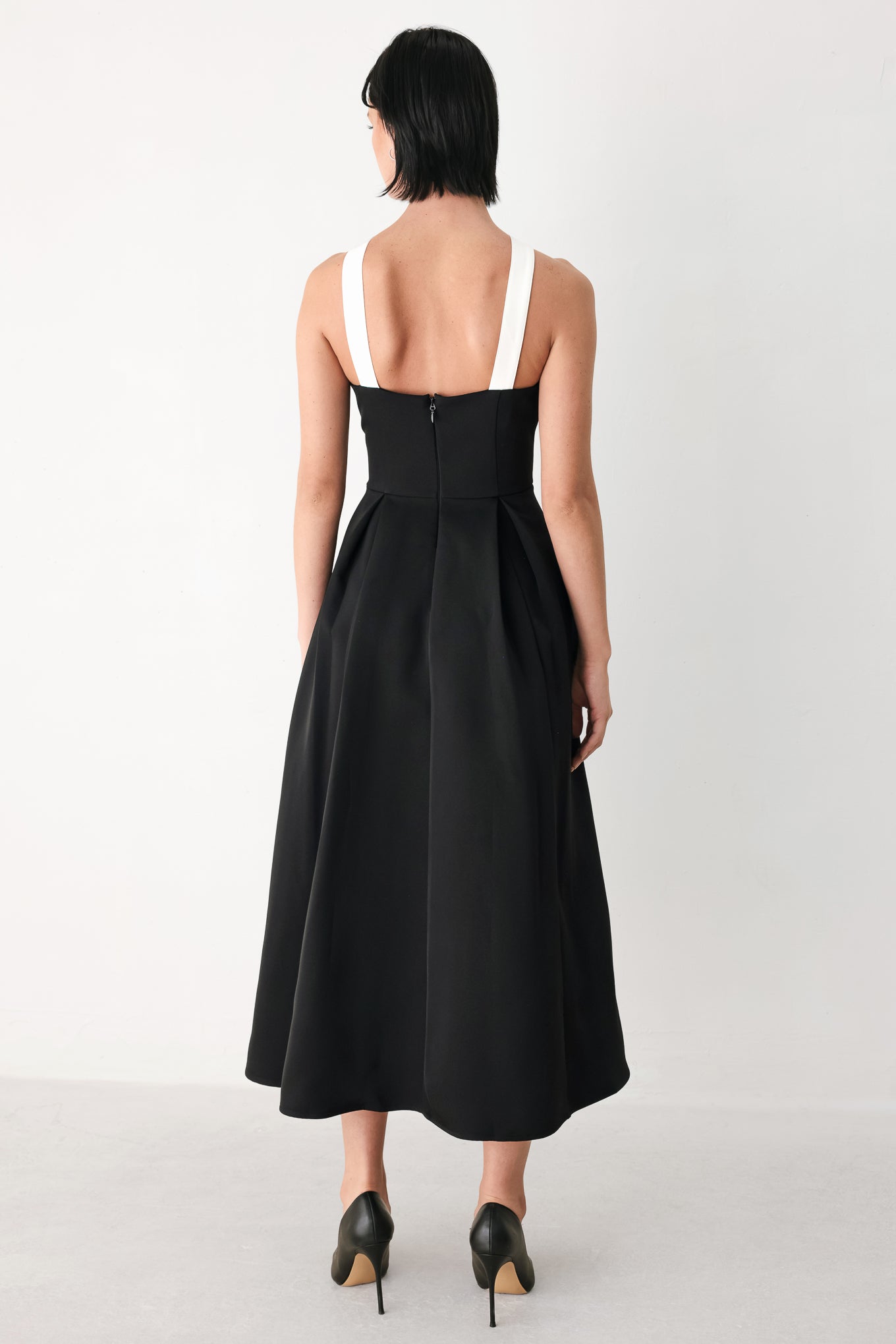 A woman modeling a black halter midi dress with a contrasting white bow at the neckline | FREEMARKET