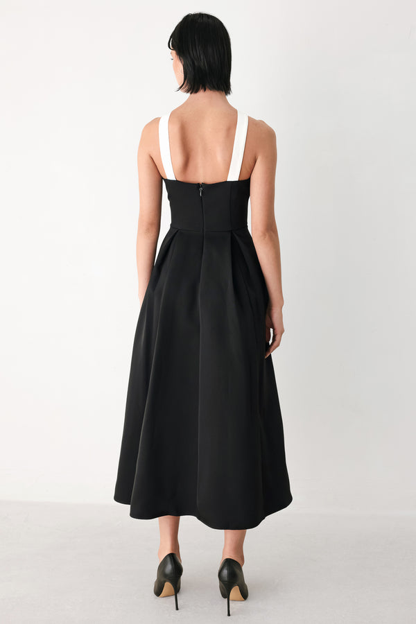 A woman modeling a black halter midi dress with a contrasting white bow at the neckline | FREEMARKET