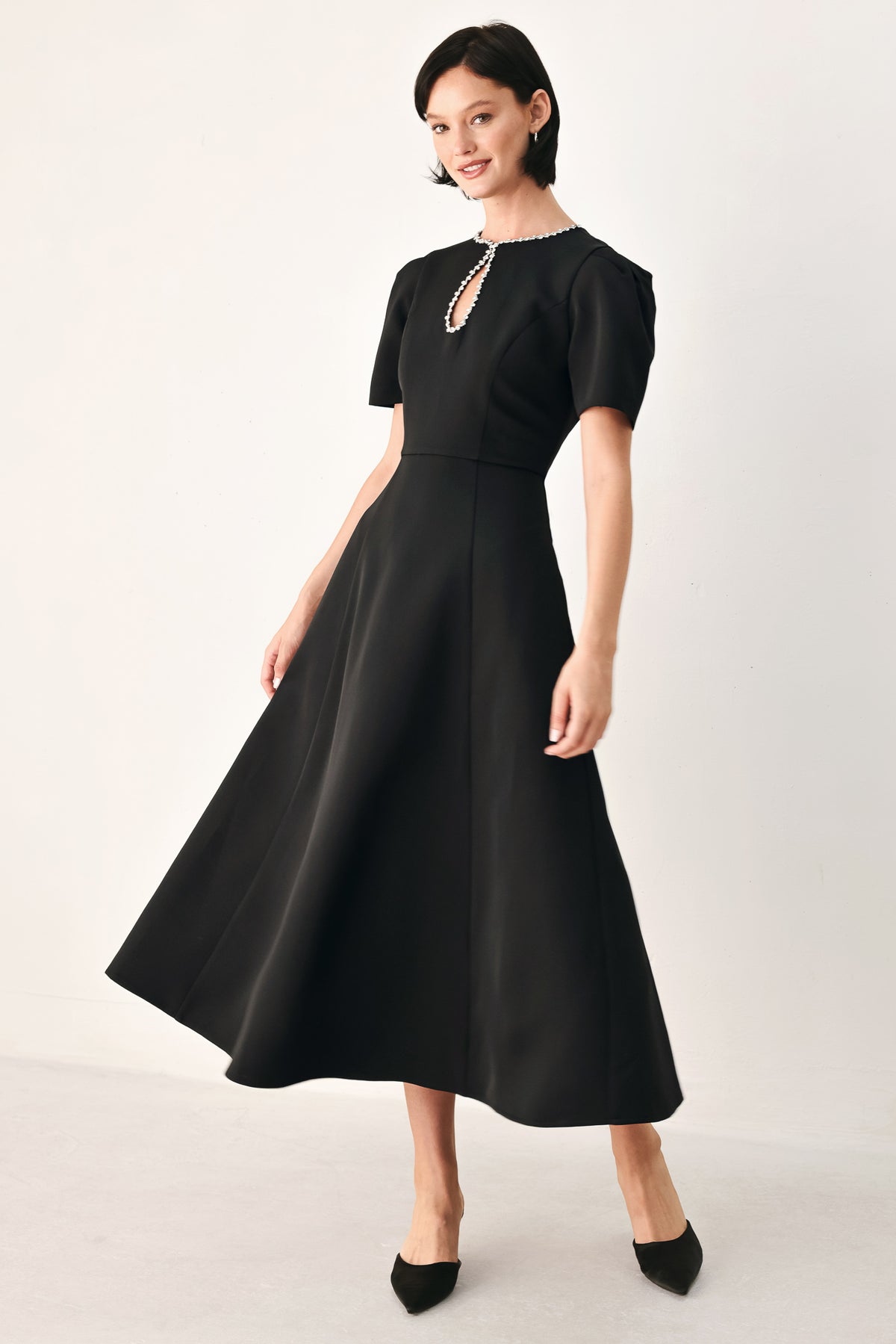A woman modeling a black midi dress with short puff sleeves, a keyhole neckline with rhinestone embellishments, and a flared skirt | FREEMARKET