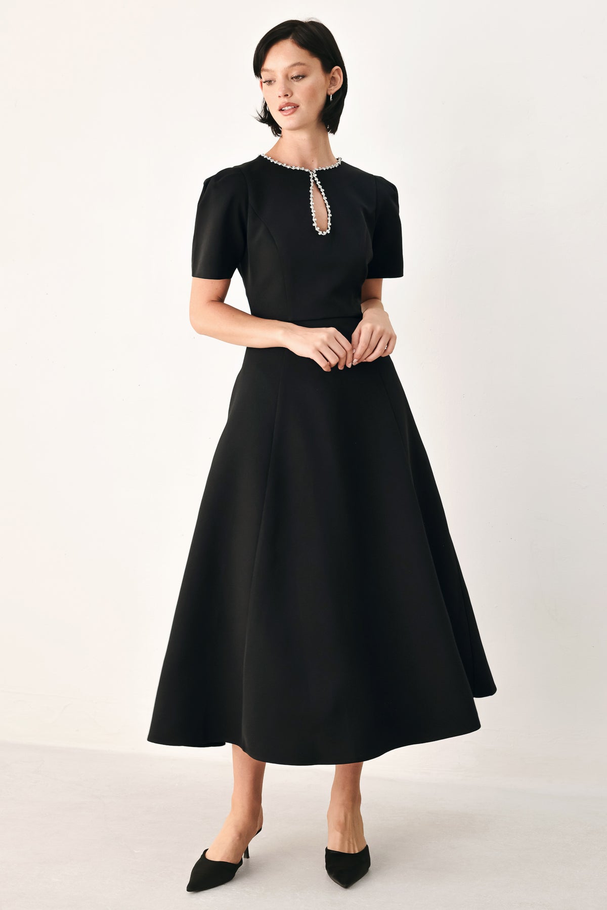 A woman modeling a black midi dress with short puff sleeves, a keyhole neckline with rhinestone embellishments, and a flared skirt | FREEMARKET