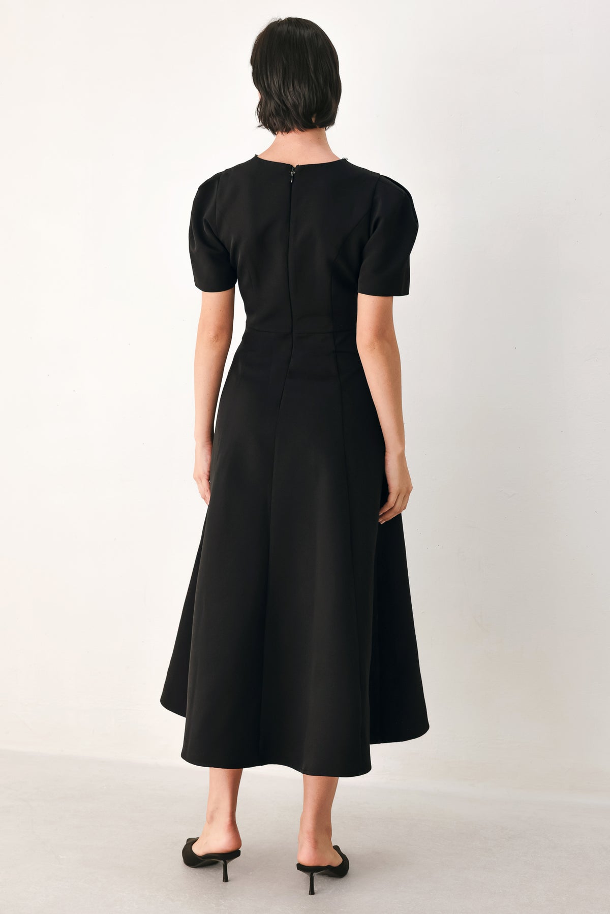 A woman modeling a black midi dress with short puff sleeves, a keyhole neckline with rhinestone embellishments, and a flared skirt | FREEMARKET
