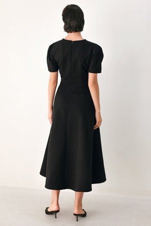 A woman modeling a black midi dress with short puff sleeves, a keyhole neckline with rhinestone embellishments, and a flared skirt | FREEMARKET