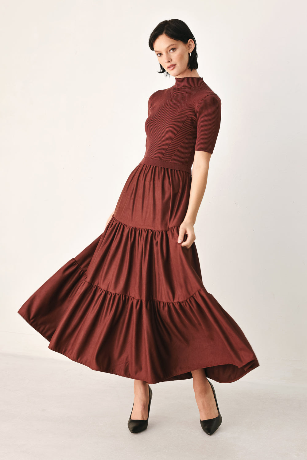 A woman modeling a rust-brown tiered midi dress with short sleeves and a mock neck | FREEMARKET